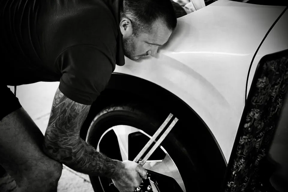 Calgary paintless dent repair technician sighting the reflection along a car panel